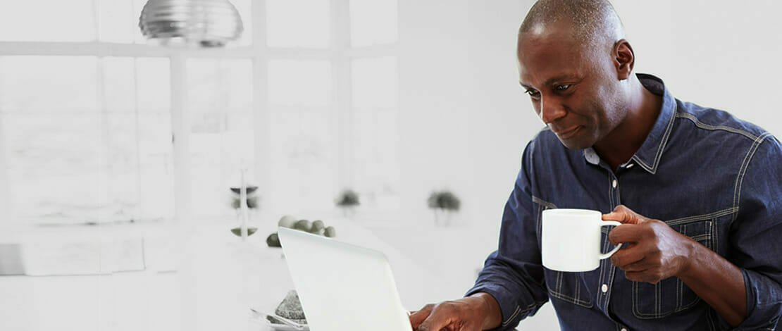 Man drinking coffee at computer