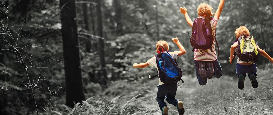 children with backpacks jumping